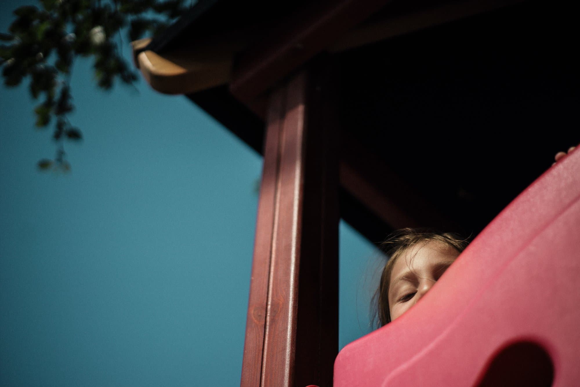 Child peeking out from behind a red post