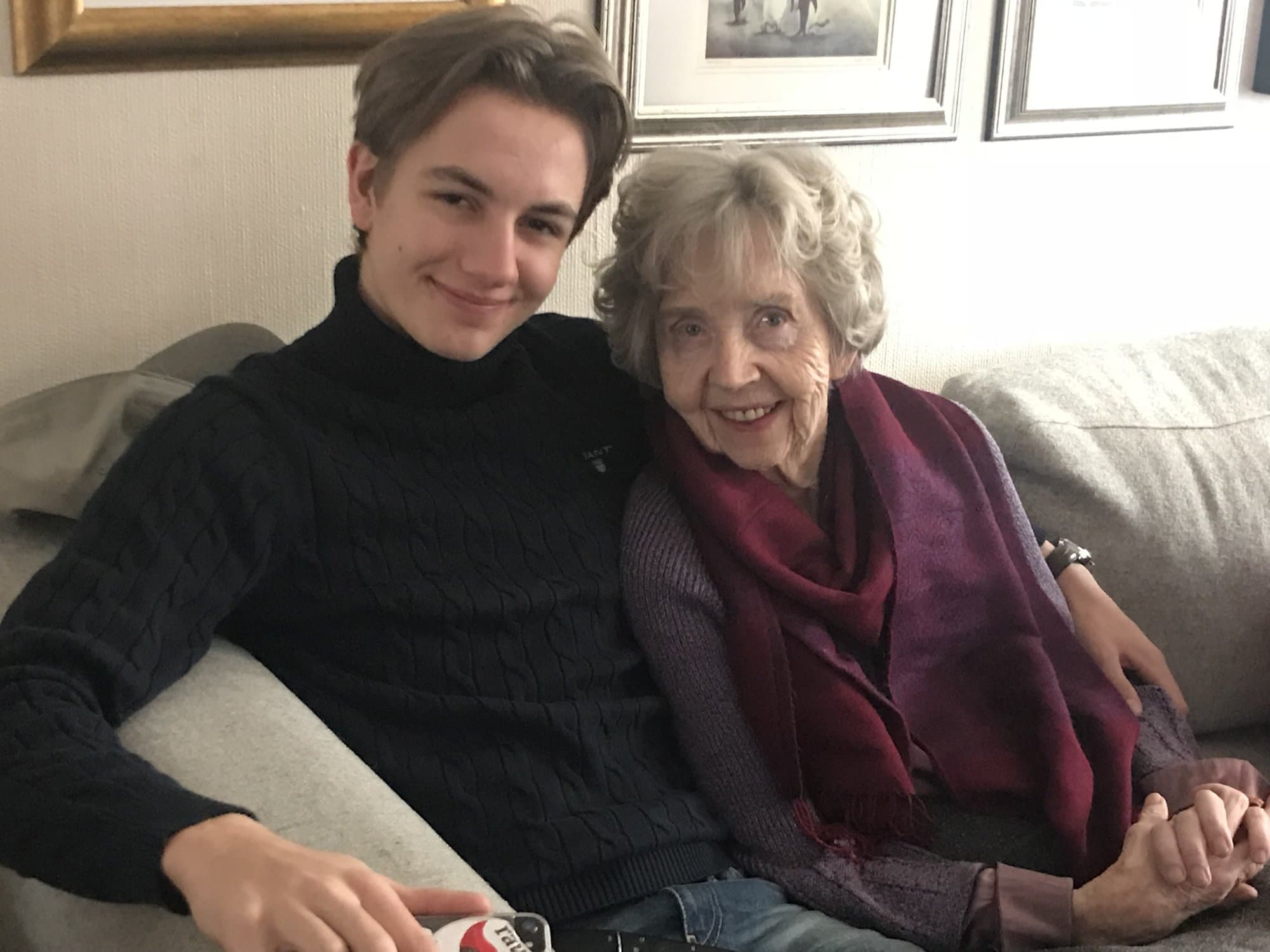 Young man and older woman sitting close together on a sofa
