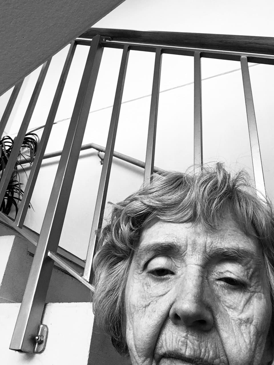 Older woman seen from below in a stairwell, black and white