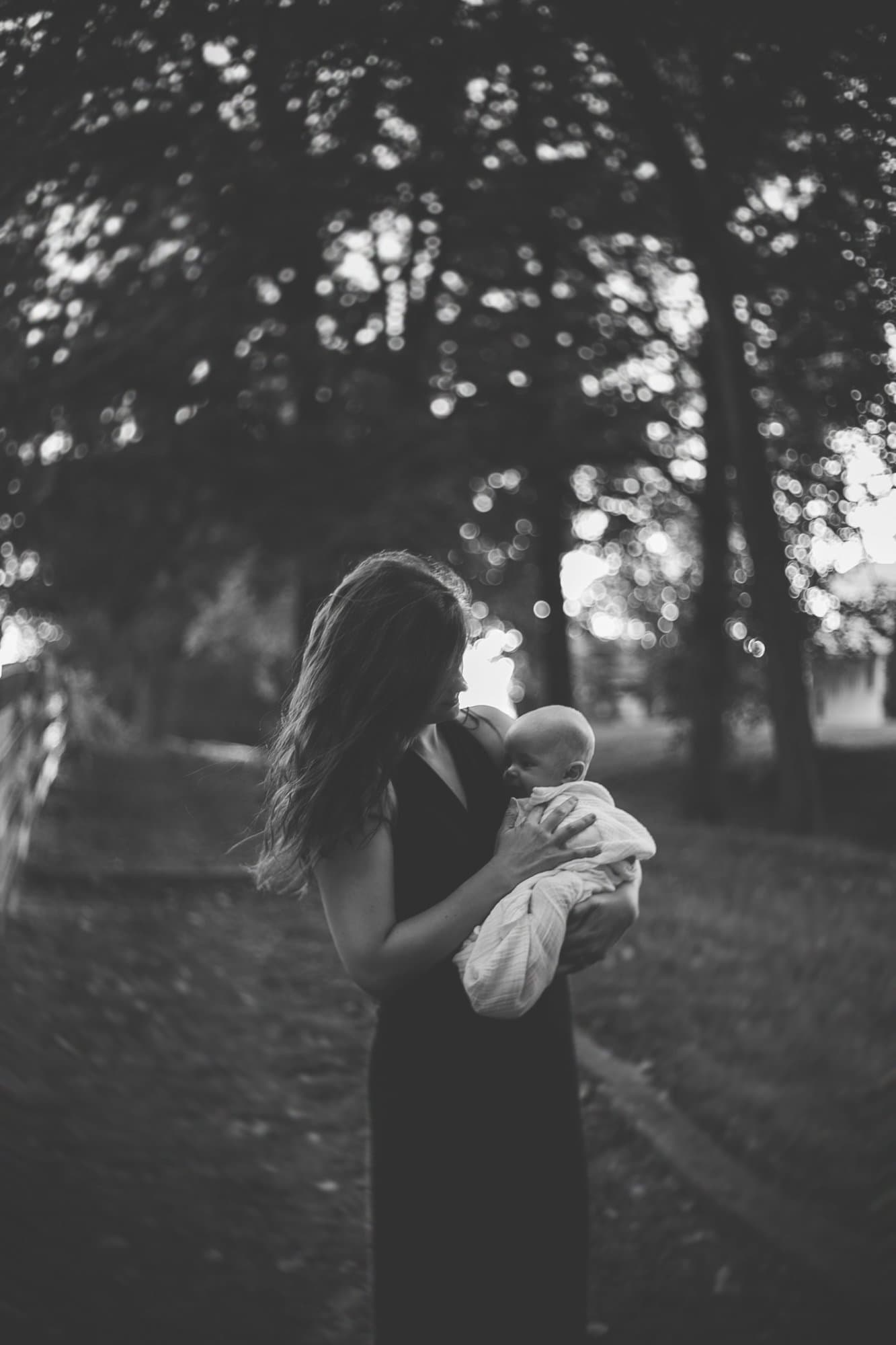 Mother holding an infant in the woods, black and white
