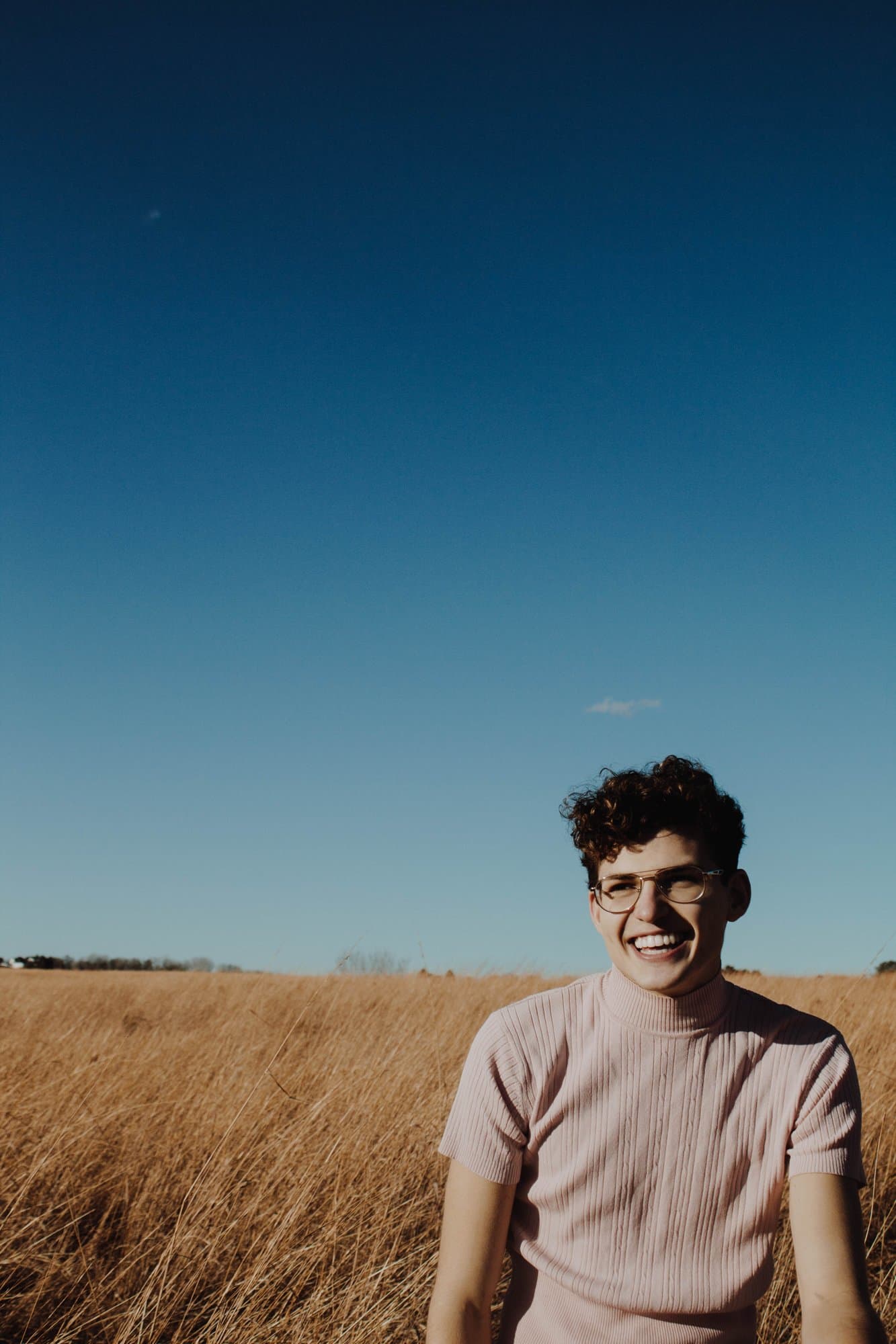 Young man standing in a field under a blue sky